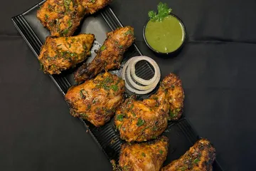 Baked tandoori chicken pieces with a wedge of lemon